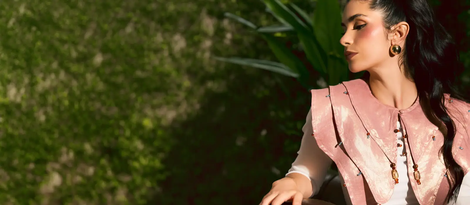 Felix Matos editorial slider image featuring a model wearing a pink statement top with layered collar details against a natural outdoor background.