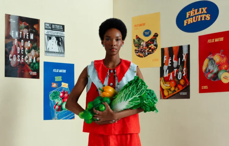 Editorial image for a Felix Matos launch blog post featuring a model in a red outfit holding vegetables in front of campaign posters from the En Tiempos de Cosecha collection.
